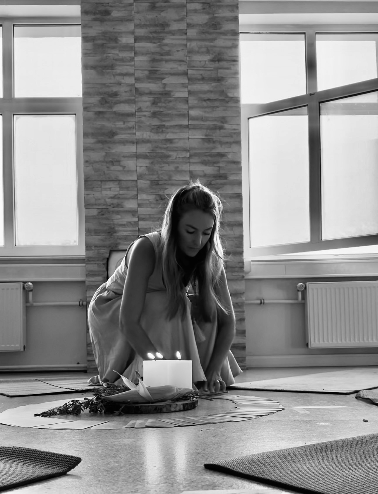 Stephanie richtet in einem hellen Raum die Mitte des Frauenkreises mit Kerze, Holzscheibe und Karten